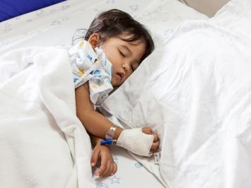 A sick child asleep on a hospital bed
